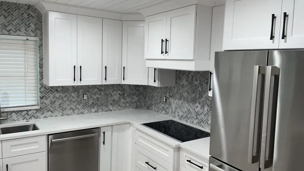 Renovated white kitchen with black hardware and herringbone backsplash